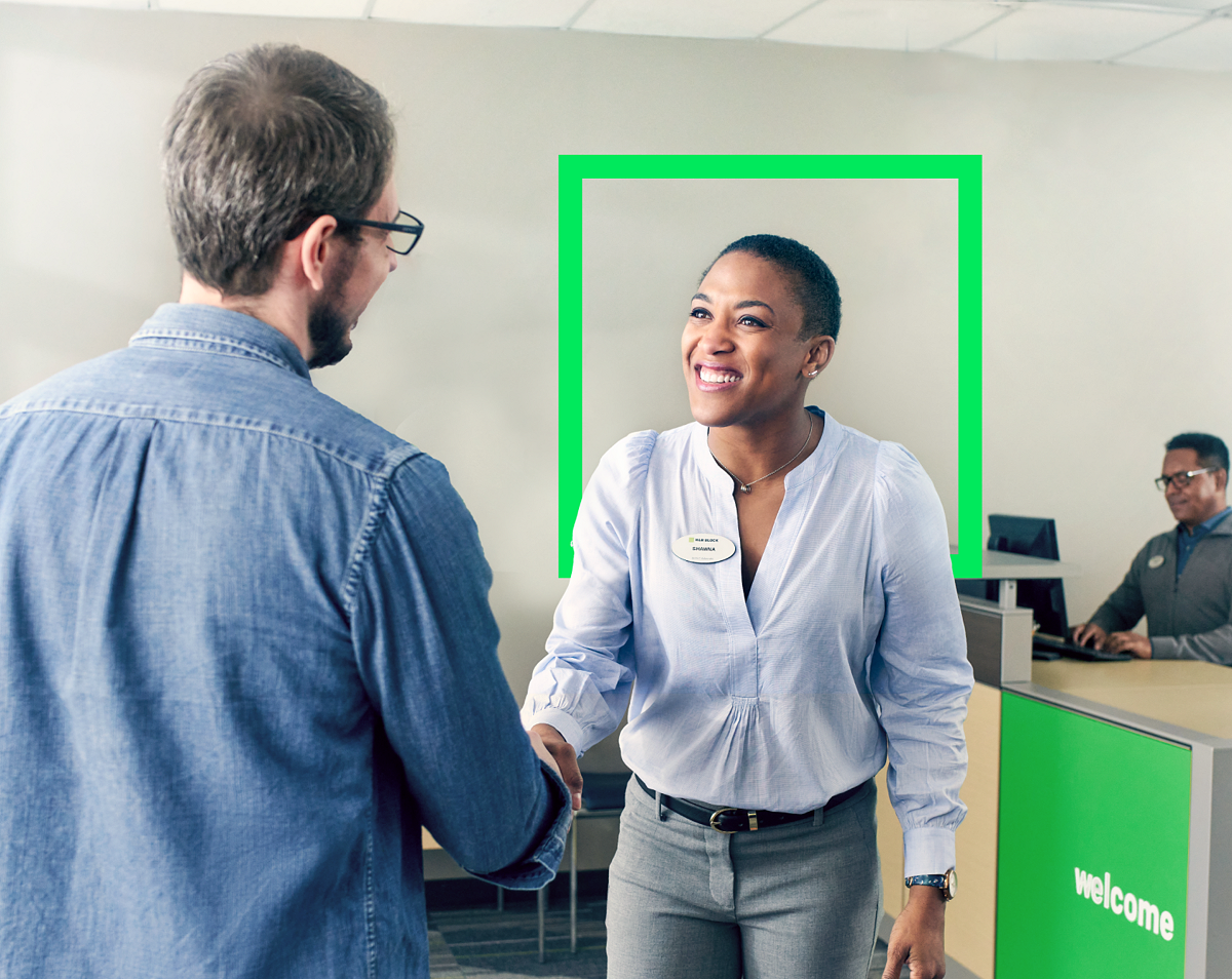 female tax pro greeting male client with handshake and smile in a tax office