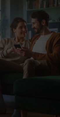 two people sitting together on a couch reviewing tax filing options on a smartphone, representing H&R Block’s user-friendly experience compared to TurboTax