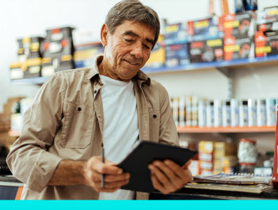 A small business owner looking at a tablet within his store